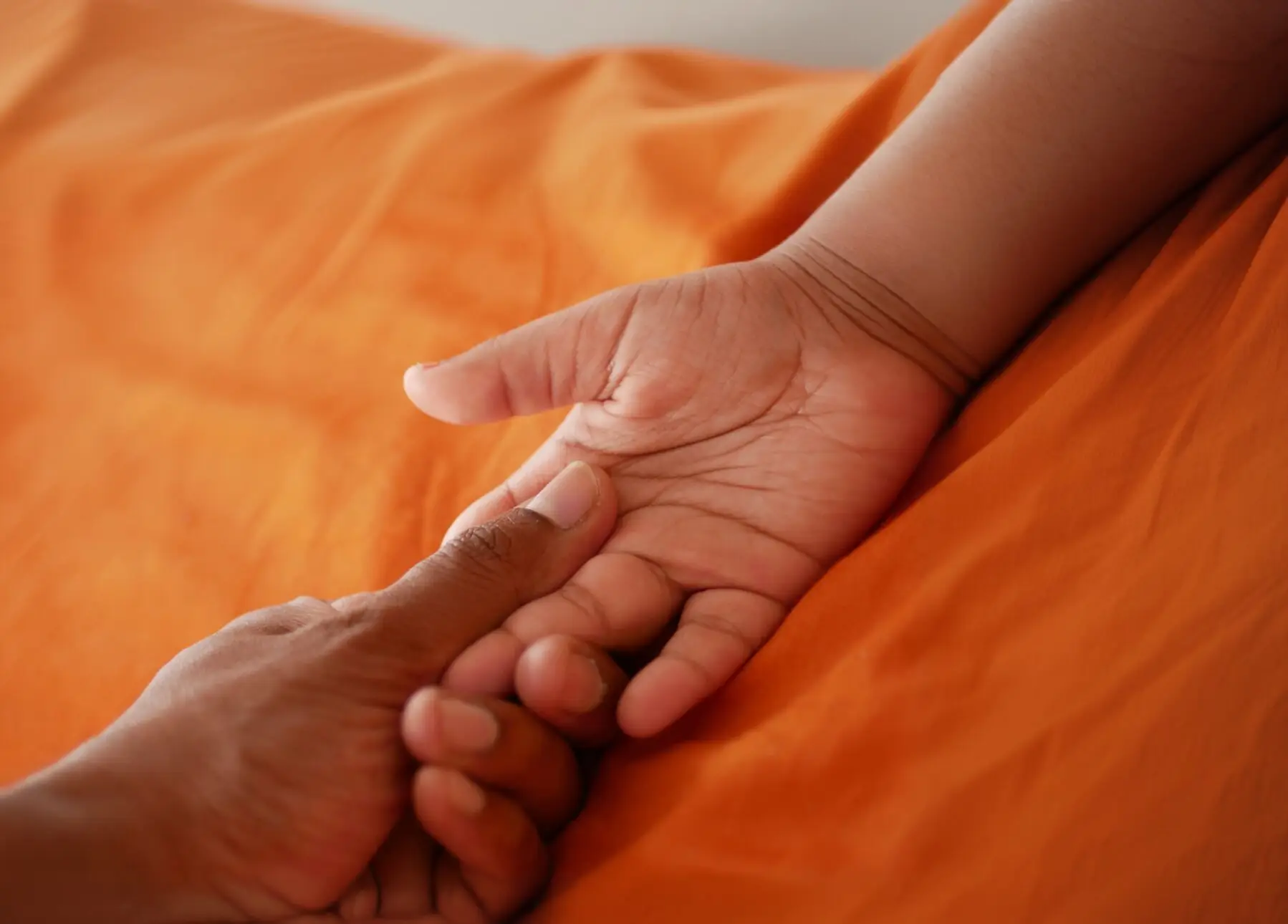 La mano de un adulto sosteniendo la mano de un bebé