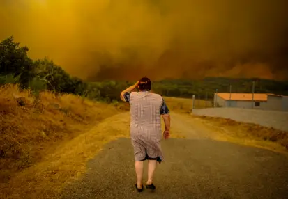 Señora mayor de espaldas viendo un incendio forestal