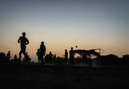 Jóvenes jugando a pelota al atardecer.