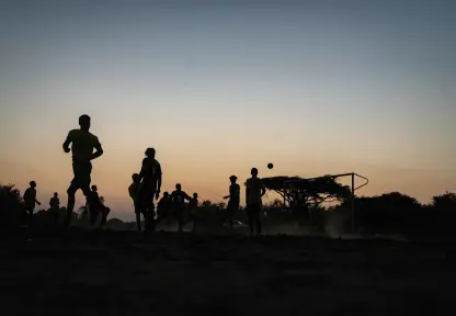 Jóvenes jugando a pelota al atardecer.