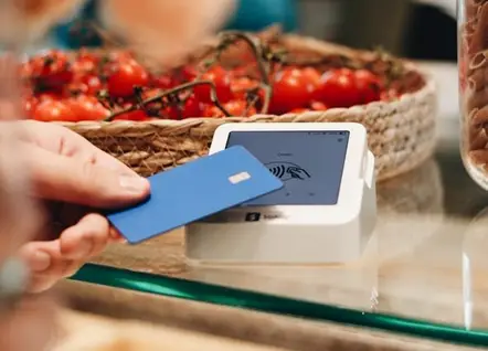 Una clienta pagando con tarjeta contactless en el mostrador de una tienda