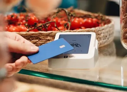 Une cliente paie sans contact par carte au comptoir d'un magasin