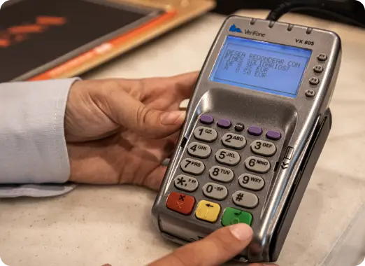 Close-up of a card payment terminal with a shopper's hand, illustrating charity rounding up at checkout