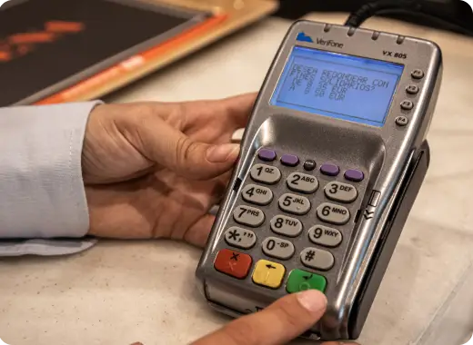 Close-up of a card payment terminal with a shopper's hand, illustrating charity rounding up at checkout