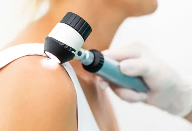 Médico examinando un lunar en el hombro de un paciente mediante un dermatoscopio manual