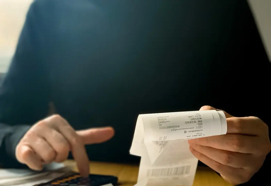 Manos con un ticket y una calculadora