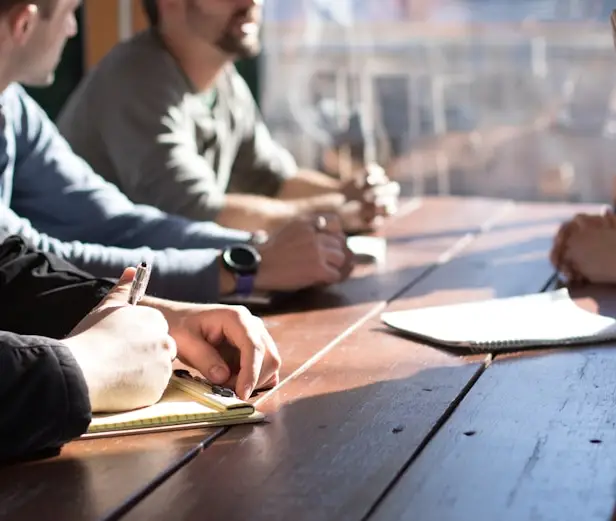 Compañeros tomando notas alrededor de una mesa
